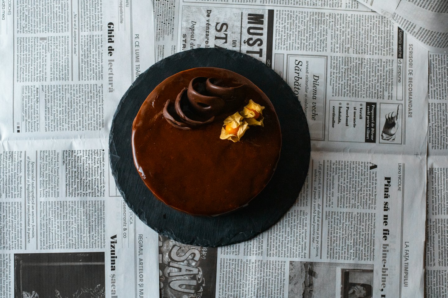 Chocolate cake with ganache and fruit on a slate board.