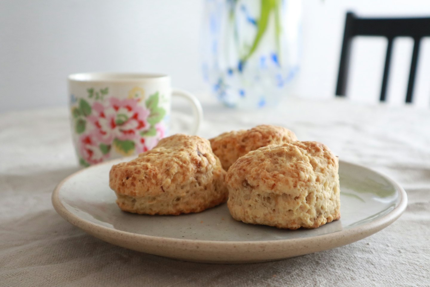 Three golden-brown scones on a ceramic plate.