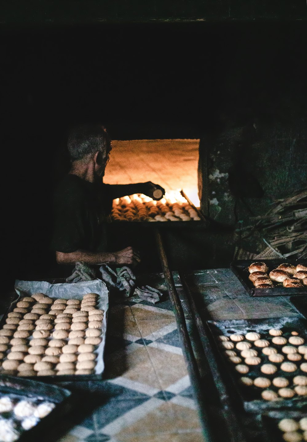 A baker places biscuits into a traditional wood-fired oven.
