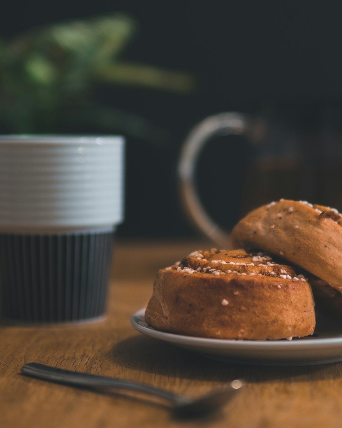Two golden cinnamon rolls on a white plate on a wooden table.